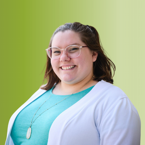 Person wearing a teal top with a white cardigan and a long necklace, against a green gradient background.