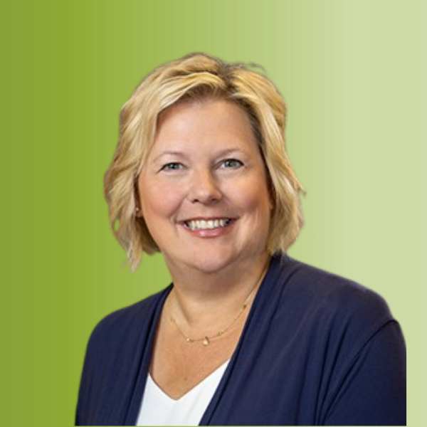 Person wearing a white top with a dark blue cardigan and a delicate gold necklace, against a green gradient background.