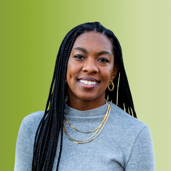 Person wearing a light gray turtleneck sweater with long braided hair and layered gold necklaces, against a green gradient background.